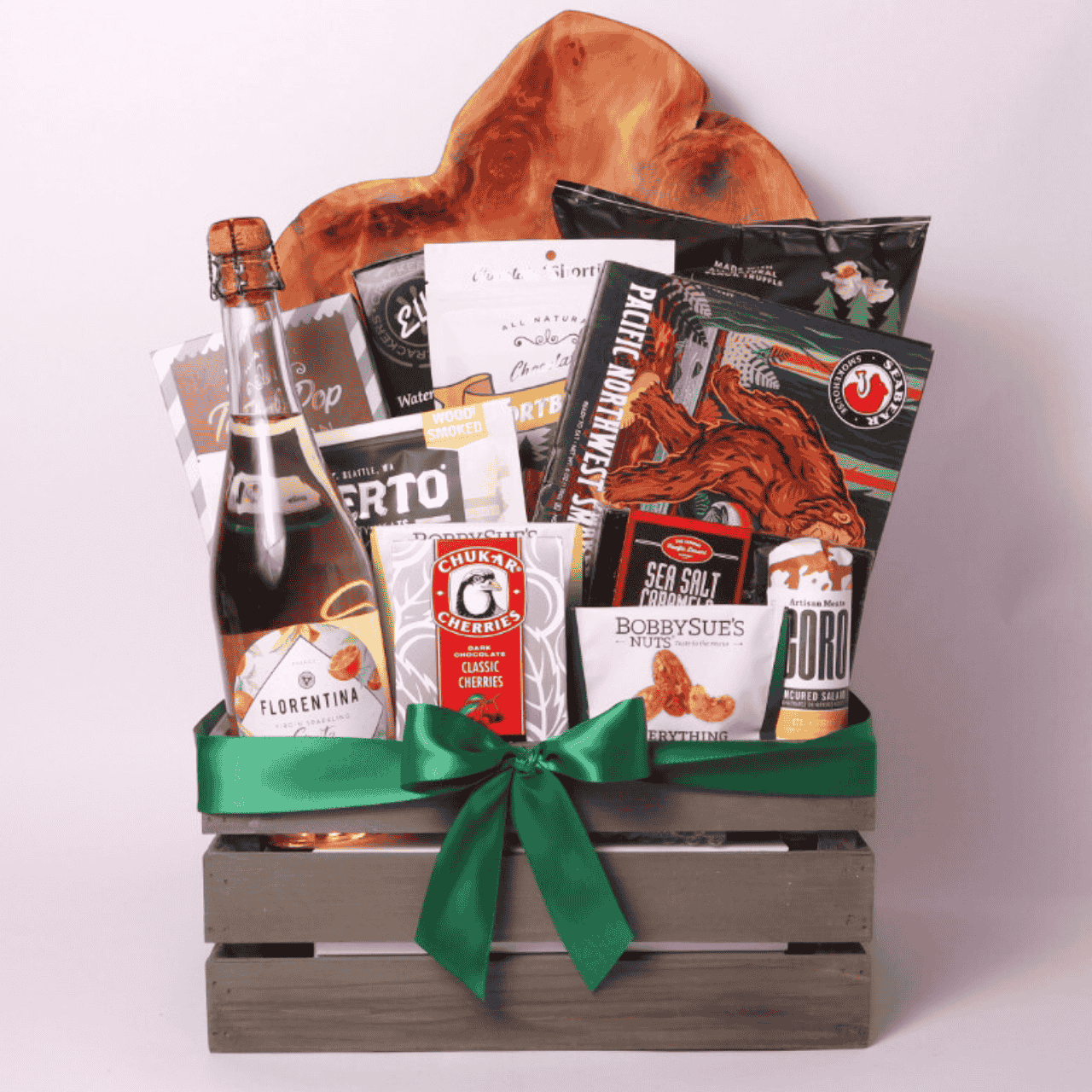 A beautifully curated Best of the Northwest gift basket filled with premium regional snacks, including smoked salmon, chocolates, nuts, and a bottle of Florentina spritz, elegantly wrapped in a wooden crate with a green ribbon.