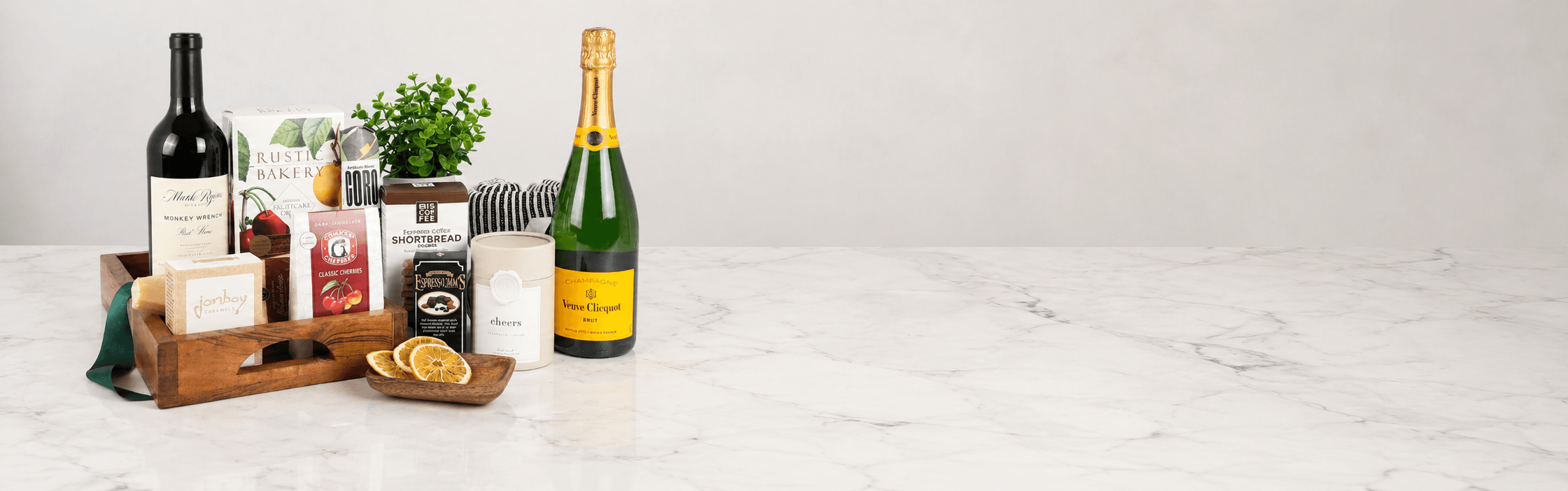 gift basket dropshipping business featuring wine, champagne and food gift set on a marble surface with a white background.