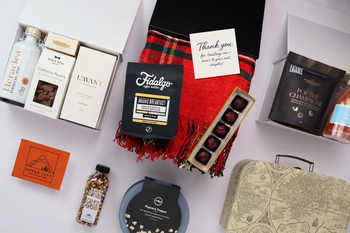 Collection of gift items including chocolates, a bottle, and a card on a white background