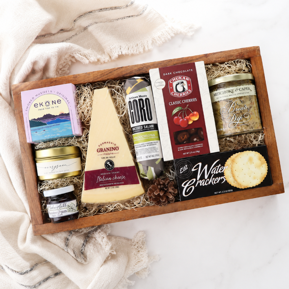 Gift box with assorted foods including cheese, salami, and cookies on a white background