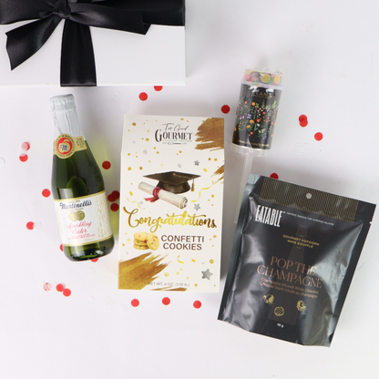 Graduation-themed gift set with champagne, cookies, and confetti on a white background.
