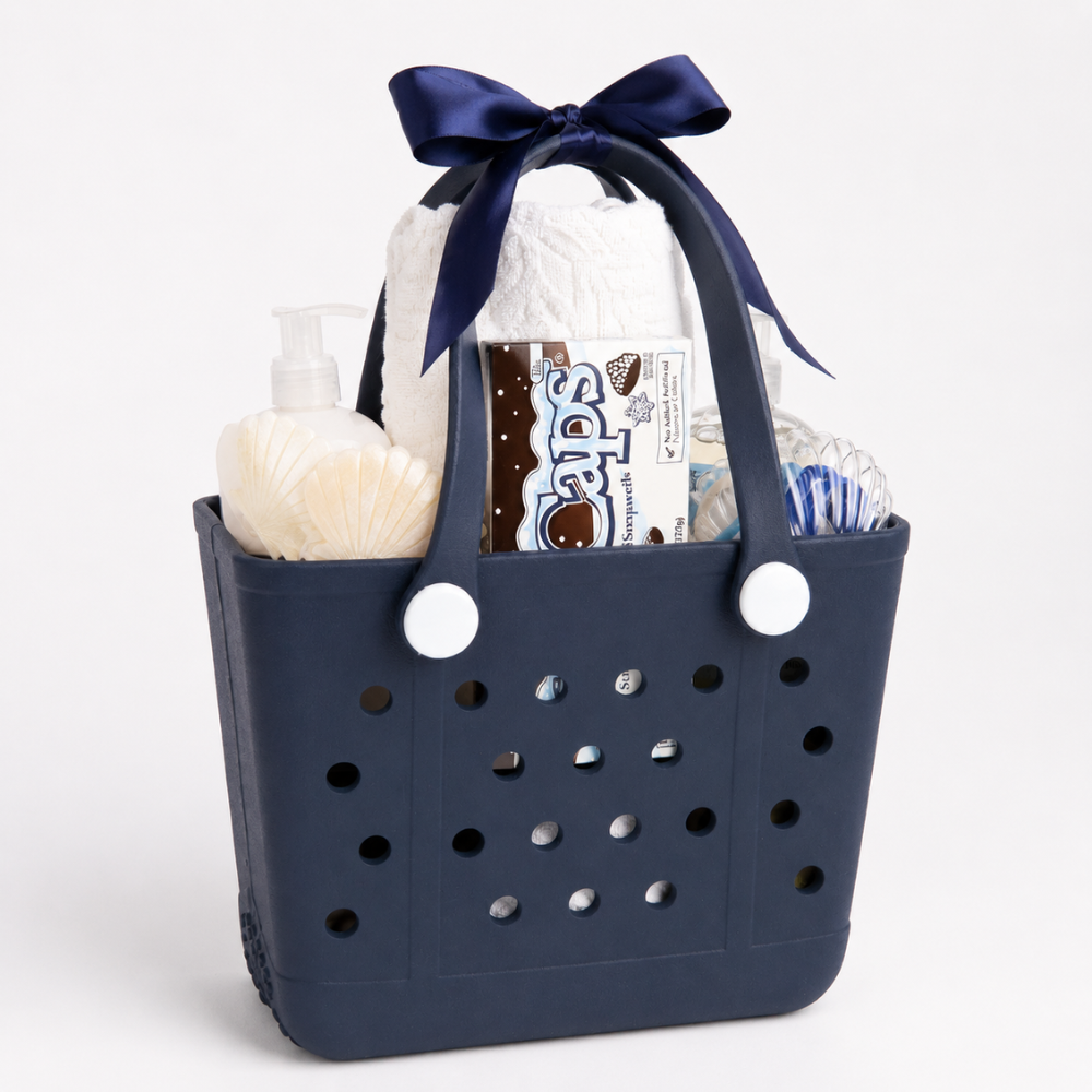 A navy blue plastic gift basket with white circular side buttons and a matching navy ribbon bow, filled with baby care items including a roll of diapers, a pump bottle, and a tube of wipes, on a white background.