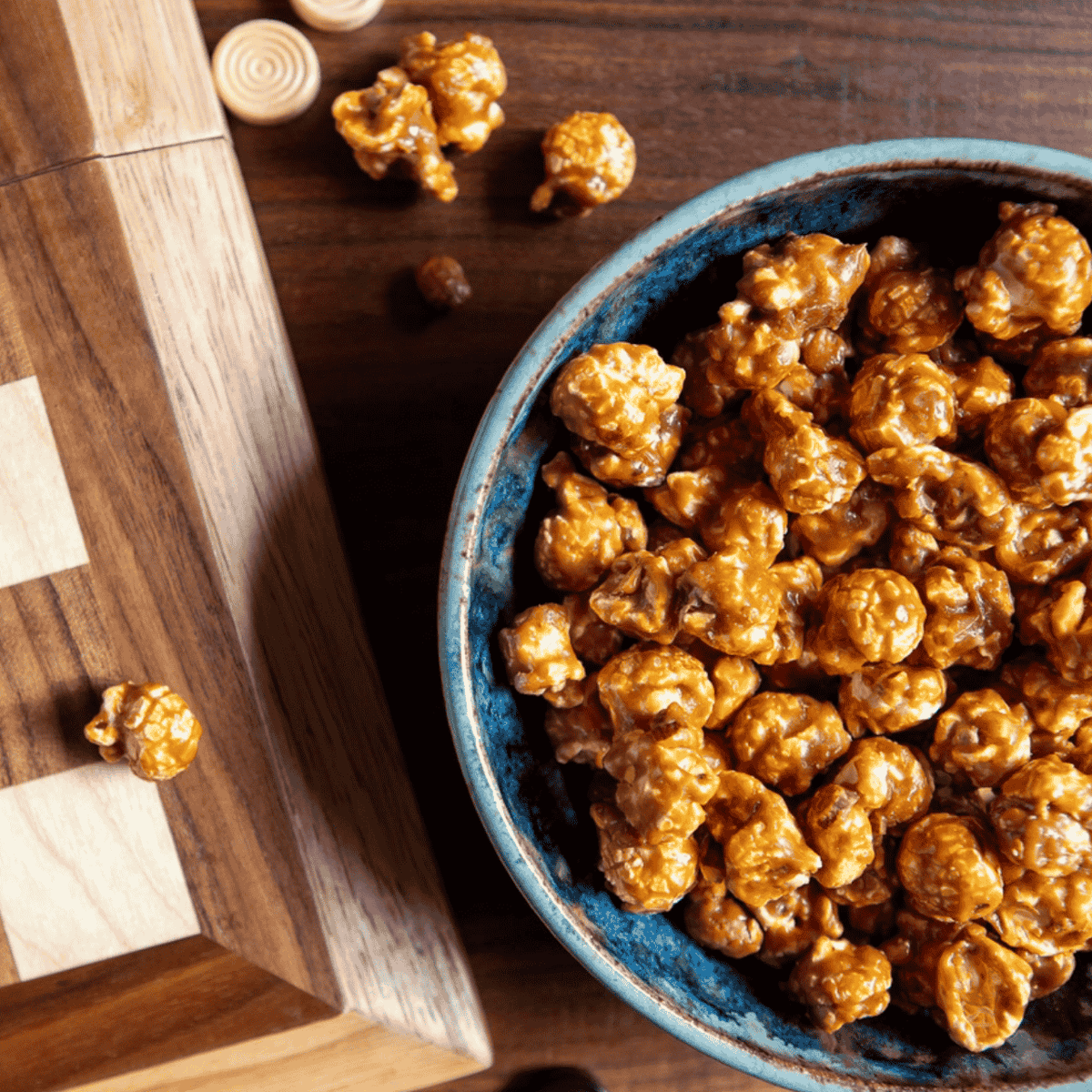 Caramel popcorn in a blue bowl on a wooden surface