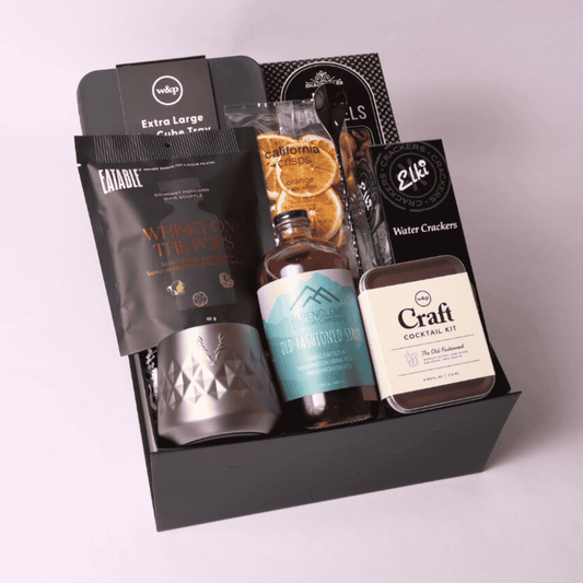Luxury old fashioned-themed gift box filled with premium items: stainless whiskey tumbler, craft cocktail kit, whiskey popcorn, ice cube mold, and more—perfect for bourbon enthusiasts.