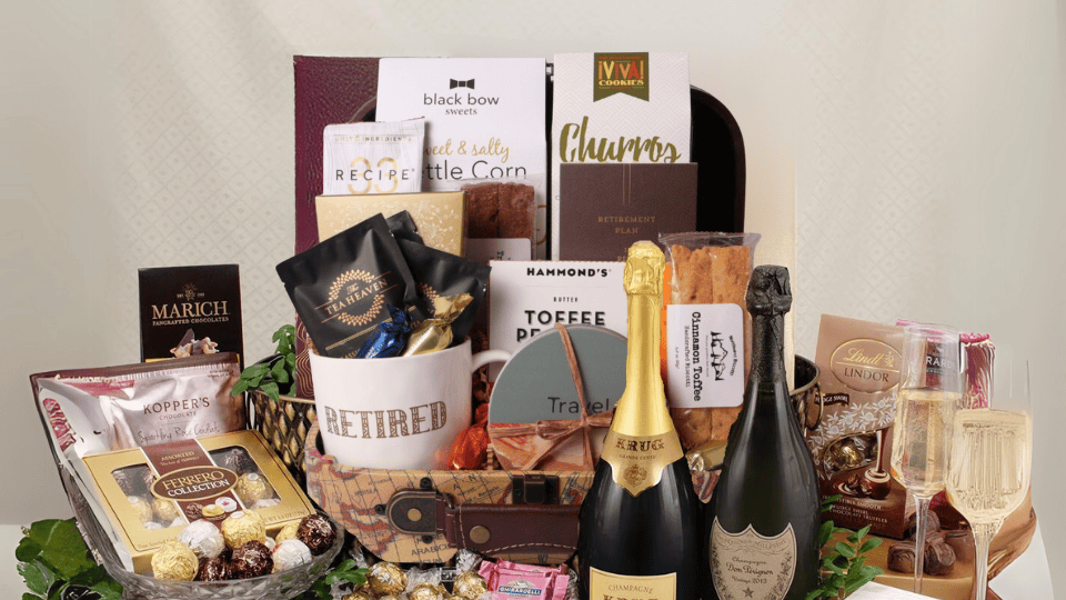 Gourmet gift basket with champagne, snacks, and other treats on a white background