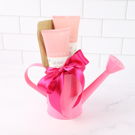 Pink watering can with a large pink bow on a white tiled background