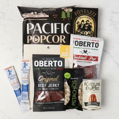 Assorted snack packages including Pacific Popcorn, Oberto beef jerky, and other branded items on a light background