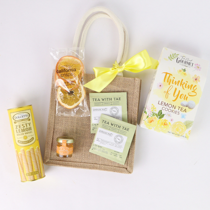 Gift set with lemon-themed products including cookies, tea, and cookies on a white background